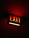 a lit exit sign in the dark next to a wall Royalty Free Stock Photo