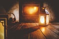 Lit lanterns on wooden table and home interior with fireplace and dark wall background. Empty copy space for your Royalty Free Stock Photo