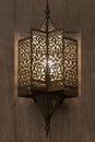 Lit, Moroccan, Arabian lamp with intricate decor hanging on wall.