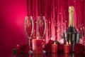 Lit red candles in transparent candlesticks illuminate a bottle and luxurious glasses with sparkling wine.