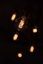 Lit spiral in a light bulb in a dark room with lit blurred bulbs on the background Royalty Free Stock Photo