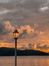 Lit street lamp on the background of a sunset in the cloudy sky over the shore Royalty Free Stock Photo