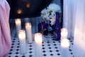 Lit tall glass cylinder candles on octagon title floor next to claw foot tub with flowers Royalty Free Stock Photo