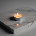 A lit tealight candle in a silver holder sits on a white marble Royalty Free Stock Photo
