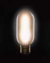 Lit tungsten filament light bulb on a black background