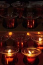 Lit and unlit white votive prayer wax candles in a Catholic church