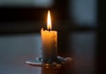 A lit white candle sits on a smooth, dark surface, with melted wax pooling around its base. The Royalty Free Stock Photo