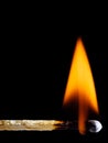 A lit wooden match burns with an orange flame isolated on black Royalty Free Stock Photo