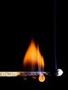 A lit wooden match flaming with an orange flame isolated on black Royalty Free Stock Photo