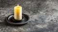 Lit yellow candle in a black holder on a gray background. Royalty Free Stock Photo