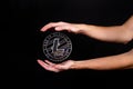 Litecoin coin and a man`s hand on a black background