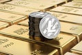 Litecoin coins laying on stacked gold bars gold ingots rendered with shallow depth of field. Concept of highly desirable cryptoc