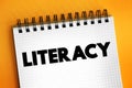 Literacy is the ability to read, write, speak and listen, text concept on notepad Royalty Free Stock Photo