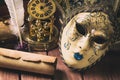 Literature concept. Still life with feather in inkstand, scroll, venetian mask, old books,vintage clock and box on wooden table. V