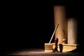 Literature and poetry concept. Old inkstand with fountain pen, blotter, seal near scrolls against black background. Dramatic light