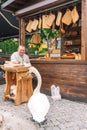 Lithuanian craftsman in traditional costumes carving wood and selling his handmade wooden artifacts