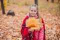 Litltle girl with woolen blanket on the soulders in the autumn park/
