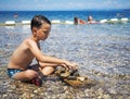 Littel boy playing in water with stones