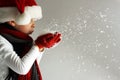 Littel boy in santa claus hat and scarf and gloves blowing snowflakes