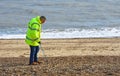 Litter picking on Felixstowe Beach by man in yellow jacket.