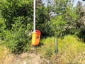 Litterbin near trees, growing near the road. Close up shot in suny day Royalty Free Stock Photo