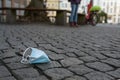 Littered surgical mask lying on a cobblestone city street, an increasing garbage problem since the outbreak of the coronavirus