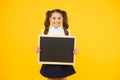 Little ad maker. Little schoolchild holding blackboard on yellow background. Little child with black-board for school