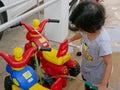 Little Asian baby girl learning to wash her plastic big bikes