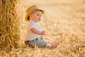 Little adorable baby boy with big brown eyes in a hat sits in a Royalty Free Stock Photo