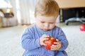 Little adorable baby girl eating big red apple. Vitamin and healthy food for small children. Portrait of beautiful child Royalty Free Stock Photo