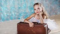 Little adorable ballerina in white tutu with old vintage suitcase in a beautiful studio. Royalty Free Stock Photo