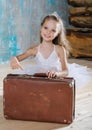 Little adorable ballerina in white tutu with old vintage suitcase in a beautiful studio. Travel and voyage Royalty Free Stock Photo