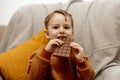 Little adorable boy sitting on the couch at home and eating chocolate bar. Child and sweets, sugar confectionery. Kid Royalty Free Stock Photo