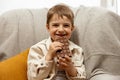 Little adorable boy sitting on the couch at home and eating chocolate bar. Child and sweets, sugar confectionery. Kid Royalty Free Stock Photo