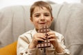 Little adorable boy sitting on the couch at home and eating chocolate bar. Child and sweets, sugar confectionery. Kid Royalty Free Stock Photo