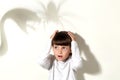 Little adorable girl being scared by shadows of snake and spider on the wall, looking away with frightened expression, keeping Royalty Free Stock Photo