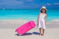 Little adorable girl with big colorful suitcase in hands on white exotic beach Royalty Free Stock Photo