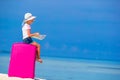 Little adorable girl with big pink suitcase and map of island on white beach Royalty Free Stock Photo