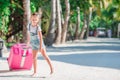 Little adorable girl with big suitcase on tropical white beach Royalty Free Stock Photo