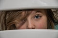 Little adorable girl child looks through a crack in a hole in a wooden fence Royalty Free Stock Photo