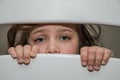 Little adorable girl child looks through a crack in a hole in a wooden fence Royalty Free Stock Photo