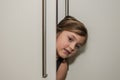 Little adorable girl child peeking out of the cabinet doors Royalty Free Stock Photo