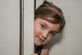 Little adorable girl child peeking out of the cabinet doors Royalty Free Stock Photo