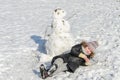 Little adorable girl child sculpts snowman from snow in winter