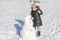 Little adorable girl child sculpts snowman from snow in winter