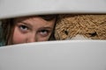 Little adorable girl child with a teddy bear looks through a crack in a hole in a wooden fence Royalty Free Stock Photo