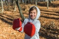 Little adorable girl child in a tracksuit, with a hood on his head, in red boxing gloves, boxing on the street in the autumn fores Royalty Free Stock Photo