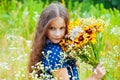 Little adorable girl gathered a bouquet of wild flowers