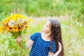 Little adorable girl gathered a bouquet of wild flowers