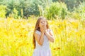 Little girl with long hair in a white dress rejoices in a field with flowers